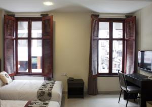 a bedroom with two beds and a desk and windows at SohoTown Hotel in Kuala Lumpur