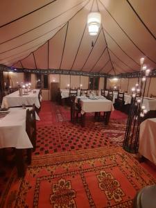 a tent with tables and chairs in a restaurant at desert camp in Hassilabied