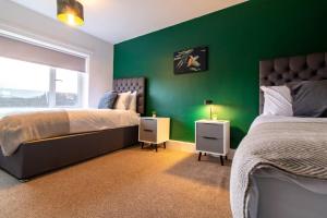 a bedroom with two beds and a green wall at K Suites - Lime Grove in Ryton