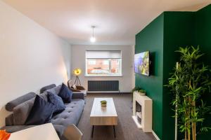 a living room with a couch and a green wall at K Suites - Lime Grove in Ryton