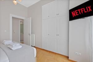 a white bedroom with white cabinets and a bed at Olympic Zeus Apartment in Athens