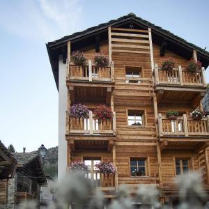 een houten gebouw met bloembakken op de balkons bij Chalet du Paradis in Cogne