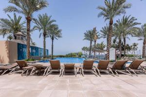 eine Gruppe von Stühlen und Tischen in einem Pool mit Palmen in der Unterkunft Frank Porter - Al Sarood in Dubai