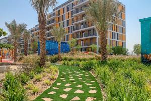 a garden with palm trees in front of a building at Frank Porter - Noor 3 Midtown in Dubai