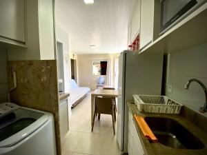 a kitchen with a sink and a table with a bed at Casinha da Praia in Aracaju