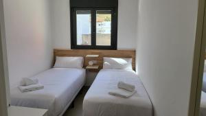 two twin beds in a room with a window at RentalSevilla La Salle in Seville
