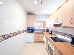 una cocina con armarios de madera y electrodomésticos blancos en La Reserva Beach & Golf Apartment en Marbella