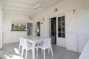 una mesa blanca y sillas en un patio en Chambres d'hôtes et villas chez Flo, en Saint-François