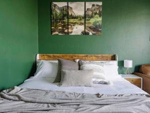 a green bedroom with a bed with three paintings on the wall at Penthouse Views & Iconic El Capitan Ambiance in Boise +29 photos