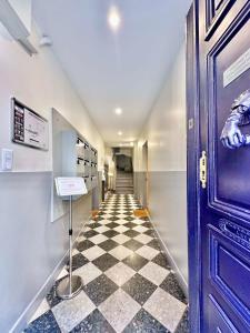 um corredor com um piso xadrez e uma porta azul em Èrsextius MMC Aix-en-Provence em Aix-en-Provence