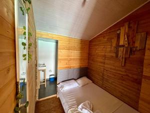 ein kleines Zimmer mit einem Bett in einer Holzwand in der Unterkunft Raw KokoMar PosadaNativa in Barú