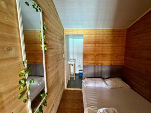 um pequeno quarto com uma cama e um espelho em Raw KokoMar PosadaNativa em Barú
