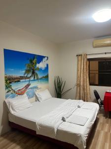 ein Schlafzimmer mit einem Bett und einem Gemälde eines Strandes in der Unterkunft Batikseafood Airport & Room in Ban Bo Sai Klang