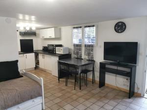 Una sala de estar con cocina y una mesa con televisión. en studio rez-de-chaussée jusqu'à 4 personnes, en Joué-lès-Tours