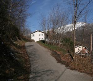 uma estrada que leva a uma casa branca com uma montanha coberta de neve em Les Appartements de Clélia em Ax-les-Thermes