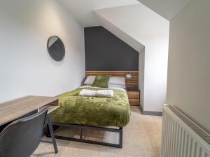 a bedroom with a green bed and a desk at Sophisticated private getaway Pass the Keys in Beeston