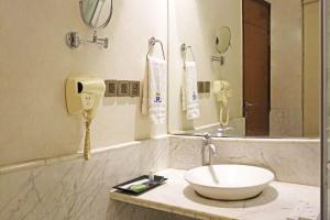 a bathroom with a sink and a mirror and a phone at Airport Hotel Claytone in New Delhi