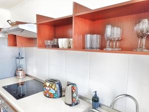 una cocina con fregadero y algunos vasos en estanterías en Apartamentos Marina del Sol, en Coquimbo