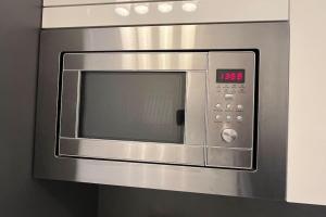 a stainless steel microwave oven with a clock on it at Residence Garden Tower - Parking in Prague