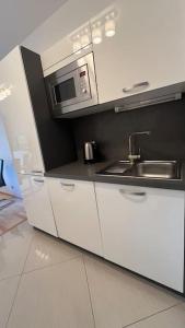 a white kitchen with a sink and a microwave at Residence Garden Tower - Parking in Prague
