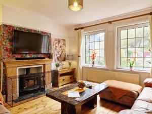 a living room with a fireplace and a tv at Blacksmiths Cottage, Bosham in Bosham
