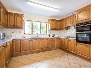 a large kitchen with wooden cabinets and a window at Bryn Llan in Bala