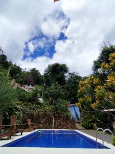 una piscina blu con sedie e alberi di CASA RANXOXITA a Itaipava
