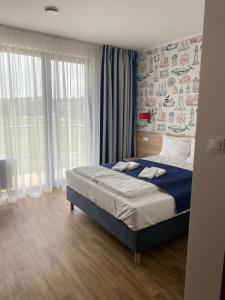 a bedroom with a bed and a large window at Faro Resort in Mrzeżyno
