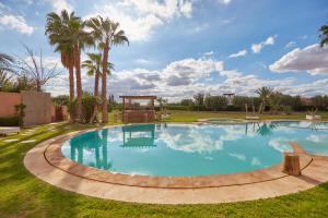 a large pool in a yard with palm trees at AG Hotel & Spa Marrakech in Marrakech