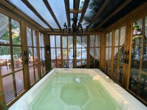uma grande banheira num quarto com janelas em Chales e Spa Exclusive - Localizado Proximo do Centro em Canela