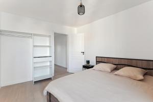 een witte slaapkamer met een bed en een kast bij Charmant T2 - Coeur d'Arpajon in Arpajon