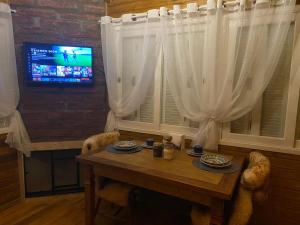 a dining room with a table and a television at Chales e Spa Exclusive - Localizado Proximo do Centro in Canela