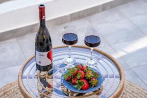 a table with two glasses of wine and a plate of strawberries at Yploui Suites in Karpathos