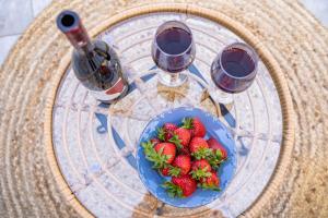 a table with a plate of strawberries and wine glasses at Yploui Suites in Karpathos