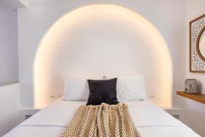 a white bed with a white headboard with a black pillow at Yploui Suites in Karpathos