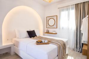 a white bedroom with two beds and a window at Yploui Suites in Karpathos