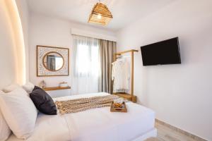 a white room with a bed and a television at Yploui Suites in Karpathos