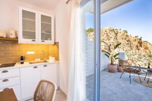 a kitchen with white cabinets and a table and chairs at Yploui Suites in Karpathos