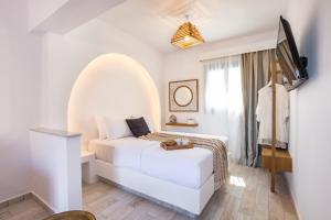 a bedroom with a bed and a flat screen tv at Yploui Suites in Karpathos
