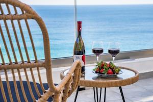a table with two glasses of wine and a bowl of strawberries at Yploui Suites in Karpathos