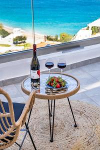 a table with two glasses of wine and a plate of food at Yploui Suites in Karpathos