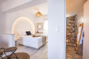 a white bedroom with a bed and a table at Yploui Suites in Karpathos