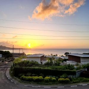 a sunset over the ocean with houses and a road at Silver View Apartments in Saint Georgeʼs