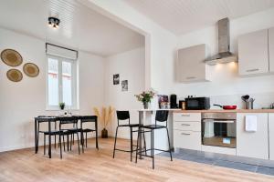 een keuken met witte kasten en een tafel en stoelen bij Maison L'Escale Paisible in Anstaing