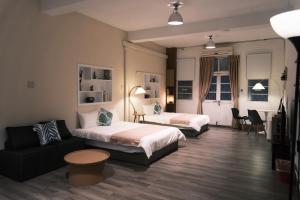 una habitación de hotel con dos camas y un sofá en Ciao潮文旅, en Tainan