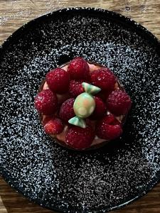 a chocolate cake with strawberries on a black plate at Affittacamere Ciccio e Pinolo in La Spezia