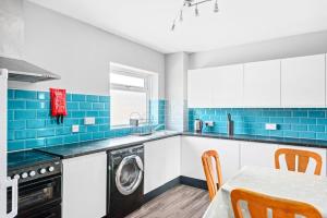 eine Küche mit einer Waschmaschine und einem Tisch mit Stühlen in der Unterkunft K Suites - Riding Leaze in Avonmouth