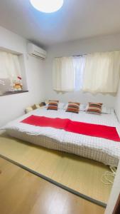 Cama grande en habitación con manta roja en 雲波館, en Nagoya