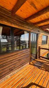 an empty porch of a wooden house with windows at Piedra que late in Tandil