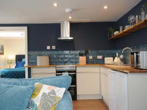 a kitchen with blue walls and a blue couch at The Bower in Helston